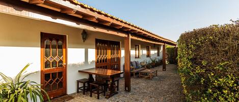 A courtyard with a cobblestone floor, wooden furniture, and a pergola.