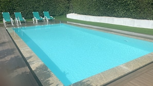 Una piscina rettangolare con superficie d'acqua cristallina, circondata da un bordo piastrellato e un basso muro bianco.