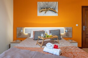 A hotel room with a bed, two bedside tables, a tray table with fruits and a towel, and a painting on the wall. - Casa Por do Sol, Grab the sun here on our warm terrace. (Ponta do Sol)