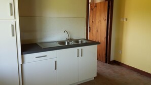 A compact kitchen with a double sink, white cabinets, and a wooden door.