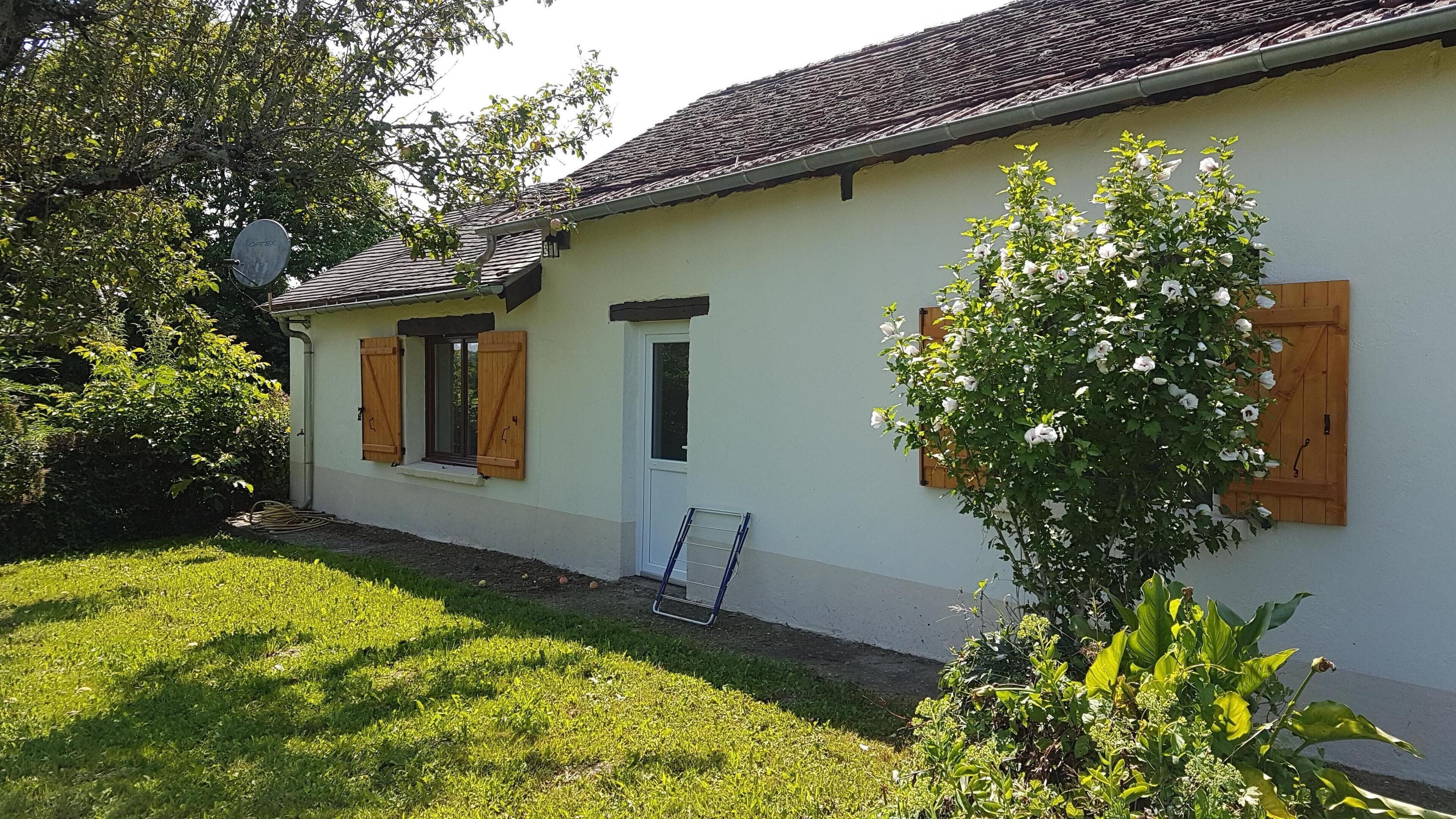 A single-story building with a tiled roof, wooden shutters, and a small window.