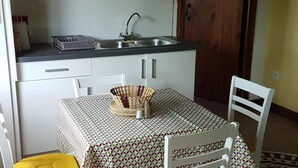 A small kitchen with a sink, a dining table with chairs, and a door in the background.