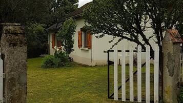 Et idyllisk hus med hvid facade, en træport og en græsplæde.