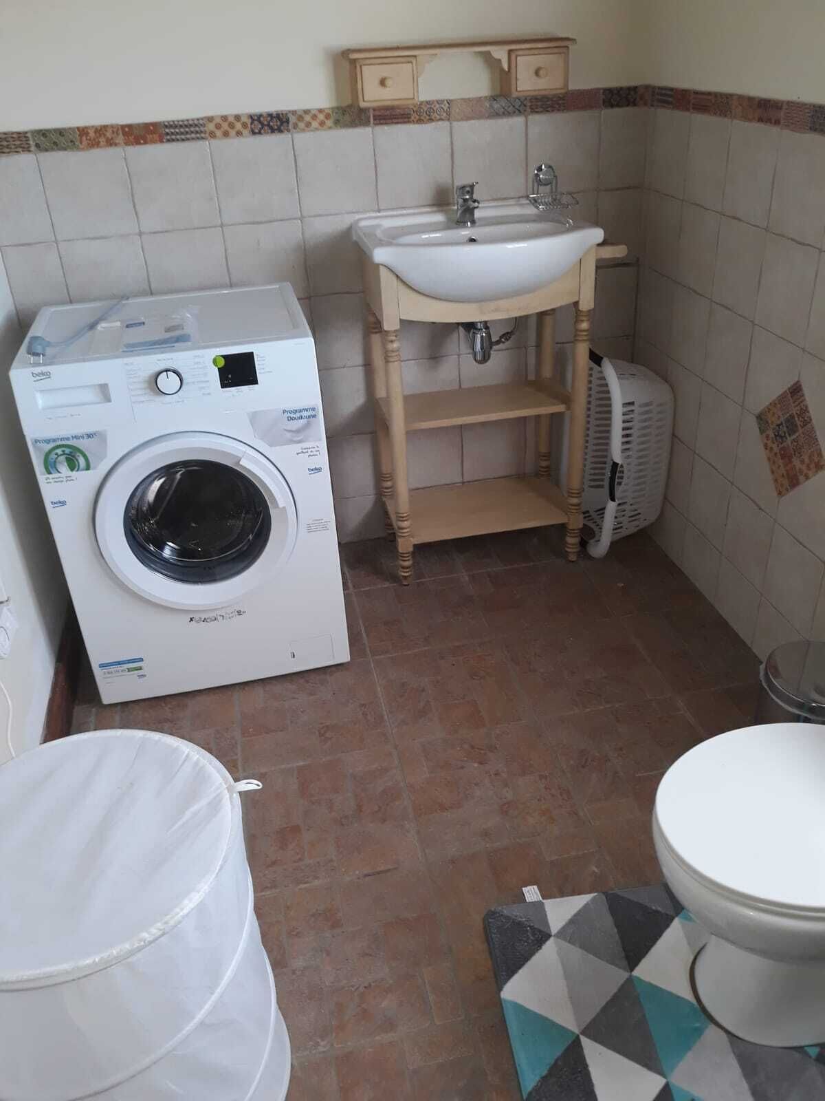 A compact bathroom with a washing machine, a sink, and a toilet.