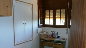 Una camera da letto con un letto, una scrivania con una sedia, una finestra con persiane e una porta.