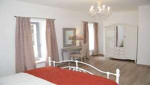 Ein Schlafzimmer mit Bett, Schreibtisch, Stuhl, Kleiderschrank und einer Chandelier.