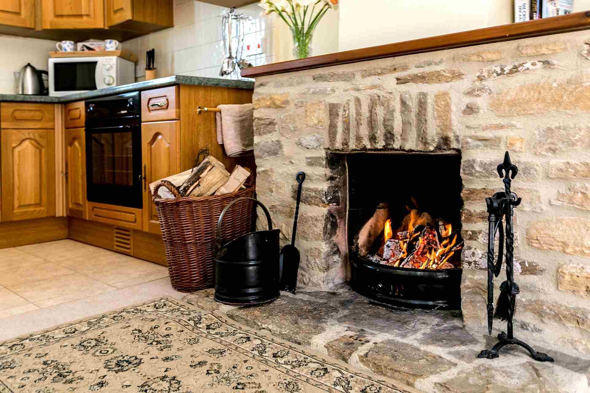 A cozy kitchen with a stone fireplace, wooden cabinets, and a microwave on the countertop.