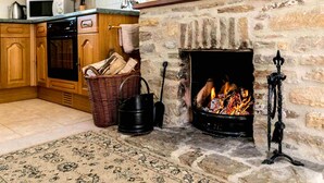 Una cocina acogedora con chimenea de piedra, armarios de madera y un microondas en la encimera.