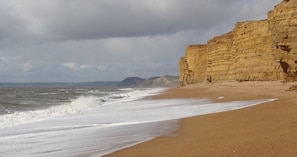 Uma praia com areal e um penhasco.