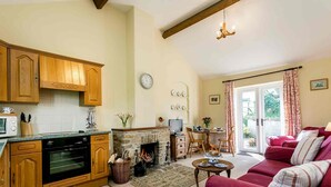 Una sala de estar acogedora con chimenea, un sofá rojo y un comedor con mesa y sillas.