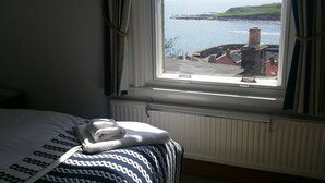 A bedroom with a view of a coastal landscape through a window. - Harbour View Apartment with panoramic sea views in Crail (Crail)