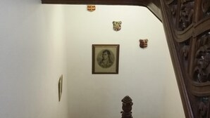 A wooden staircase with intricate carvings, a framed portrait on the wall, and a small shield decoration. - Harbour View Apartment with panoramic sea views in Crail (Crail)