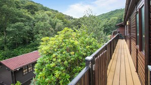 A wooden deck with a view of a forested mountain. - Two bedroom lodge within walking distance of Lynton Centre. Free fishing onsite (Lynton)