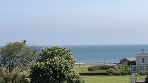 A coastal view with a grassy area, a large tree, and a building with a white facade. - Two bedroom lodge within walking distance of Lynton Centre. Free fishing onsite (Lynton)