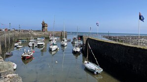 A harbor with boats docked, a stone wall, and a lighthouse in the background. - Two bedroom lodge within walking distance of Lynton Centre. Free fishing onsite (Lynton)