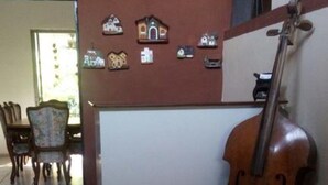 A room with a tiled floor, a wooden chair, a dining table, and a wall with small decorative items.