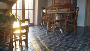 A dining area with a wooden table and chairs, a large cabinet, and a staircase with wooden beams. - Holiday home 't Ligt ter velde (Lichtervelde)