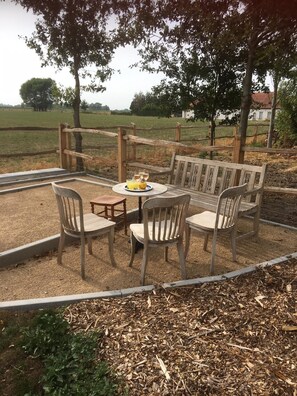 Relax in a serene outdoor setting with a bench, chairs, and a table, surrounded by a fence and a picturesque view.