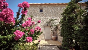 A stone building with a tiled roof, a door, and a small window.
