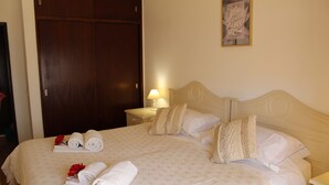Un lit bien fait, avec une couvre-lit à motifs étoilés, plusieurs serviettes enroulées et des coussins décoratifs.