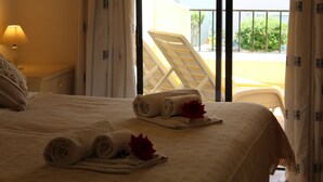 Une chambre d’hôtel avec un lit, une fenêtre avec des rideaux, une chaise à l’extérieur et une lampe sur la table de chevet.