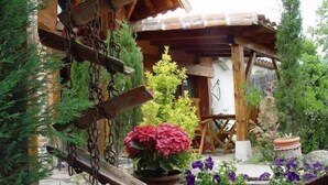 A rustic wooden building with a wooden porch and a hanging metal structure. - Rural Guest House in Olmedo (Spain) (Olmedo)