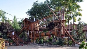 A wooden play structure with slides and climbing elements, surrounded by trees and potted plants. - Rural Guest House in Olmedo (Spain) (Olmedo)