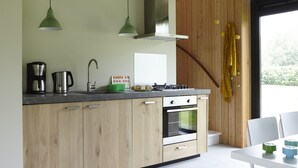 Una cocina moderna con gabinetes de madera, un lavamanos de acero inoxidable, una estufa a gas y dos lámparas colgantes.