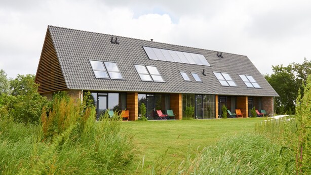 Una casa moderna con techo inclinado, ventanas amplias y un césped.