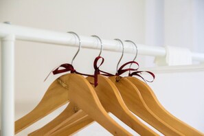 Een wit metalen rek met houten kleerhangers, vastgebonden met rode linten.