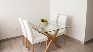 Un espace repas moderne avec une table en verre, des chaises blanches et une petite plante posée sur la table.