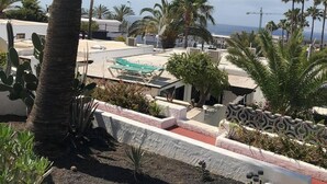 Un jardin sur le toit agrémenté de palmiers, une piscine et une vue sur l’océan.