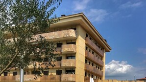A multi-story building with a swimming pool, surrounded by well-maintained grass and potted plants. - Boadella Apartment (Lloret de Mar)