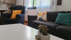 Un salon avec un canapé foncé, une table basse blanche et un cactus.