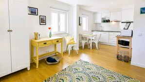 Un espacio habitable compacto con kitchenette, comedor y pequeño escritorio.