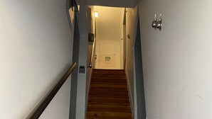 Una escalera de madera con barandilla a la izquierda y una puerta en la parte superior.
