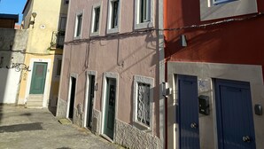 Un edificio de varios pisos con fachada roja y beige, múltiples ventanas y una puerta visible.