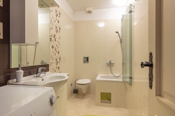 A modern bathroom with a glass shower enclosure, a white sink, and a toilet.