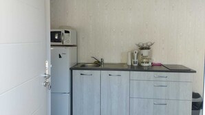 A compact kitchen with a microwave, coffee maker, and sink.