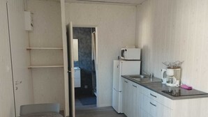 A compact kitchen with white cabinets, a countertop, a microwave, a refrigerator, and a coffee maker.