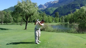 A golf course with a lake and mountains in the background.