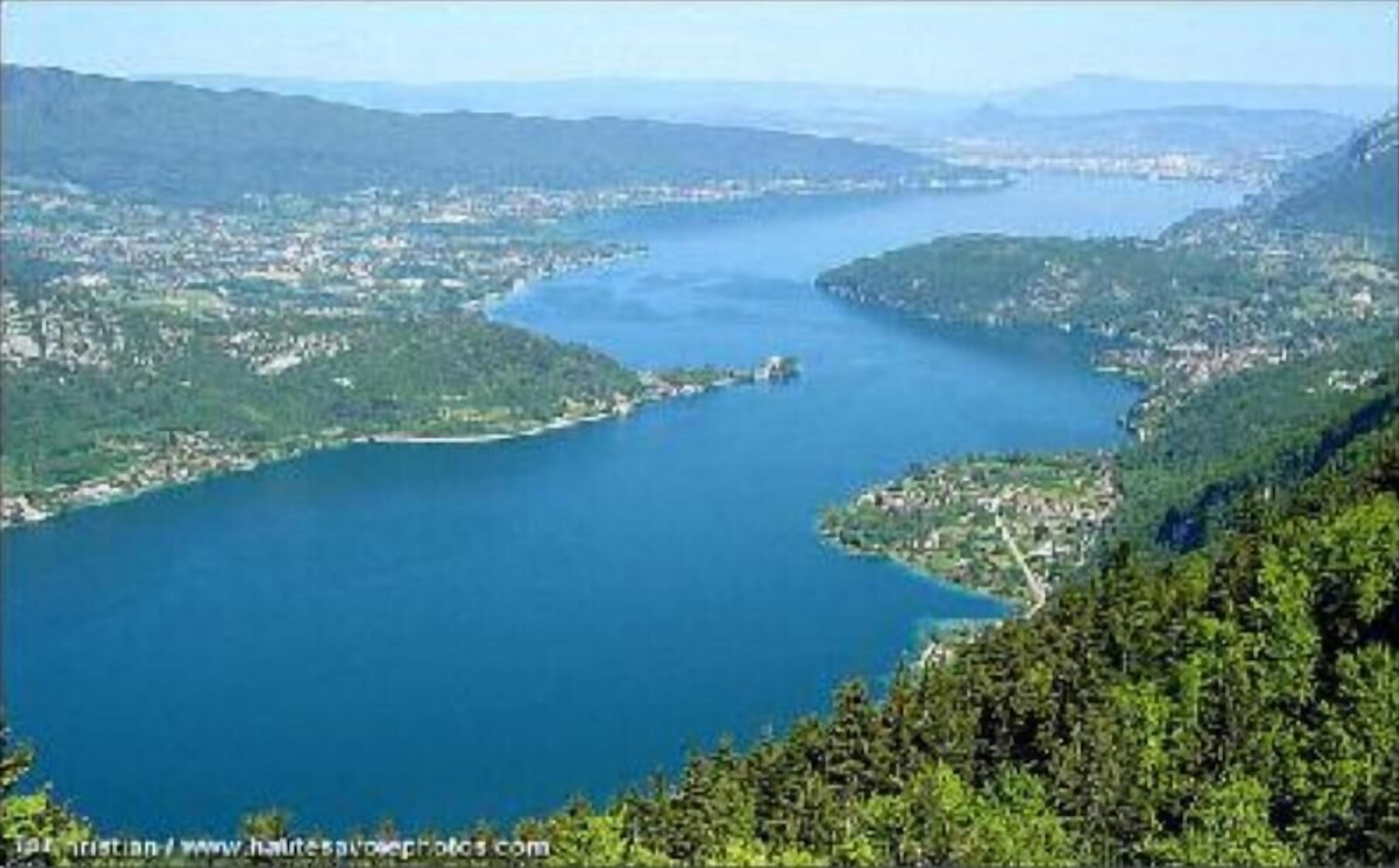 A coastal town with a large body of water, surrounded by hills and greenery.