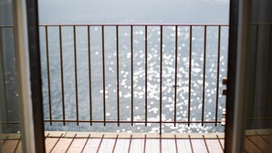A view through a metal railing with a tiled floor, leading to a body of water with reflections. - La Darsena di Riva Grande - Comballi (montrasio)