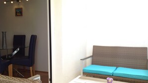 Ein Balkon mit einer Rattan-Couch, einem Tisch und Stühlen.