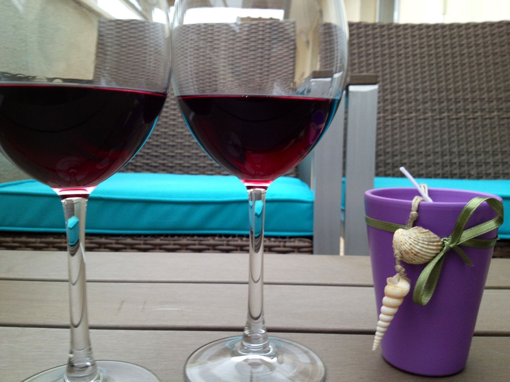 Two wine glasses filled with red wine on a wooden table.