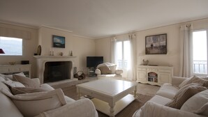 Een ruime woonkamer met een open haard, een televisie en een comfortabele zithoek.