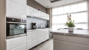 Eine moderne Küche mit weißen Schränken, einem eingebauten Backofen, einer Kaffeemaschine und einem Blumentopf.