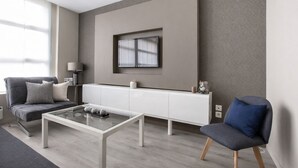 Ein modernes Wohnzimmer mit Sofa, Couchtisch, Wandfernseher und Beistelltisch.