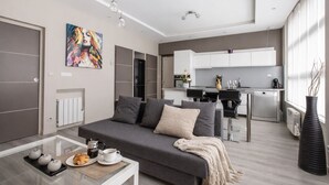 Ein modernes Wohnzimmer mit grauem Sofa, einem Couchtisch und einem Essbereich mit einer Küche im Hintergrund.