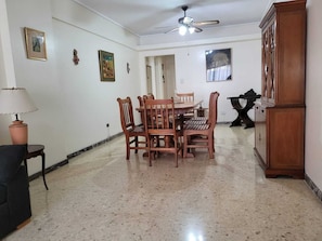 Un coin repas comprenant une table ronde et des chaises, un ventilateur de plafond et un meuble de rangement.